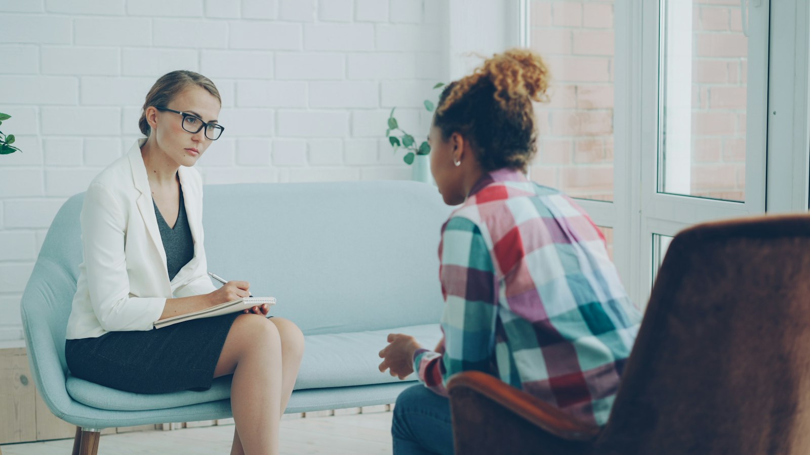 Therapist with a notepad listening to a client during a counseling session